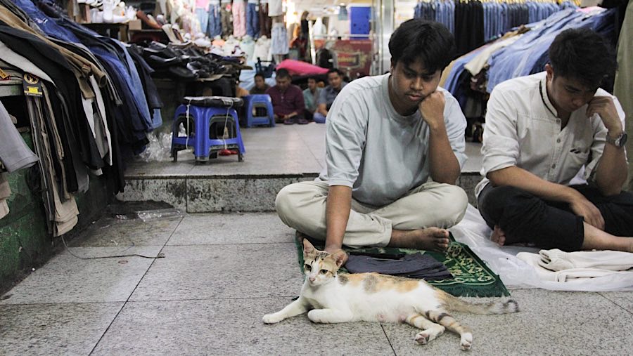 Di tengah keramaian pasar, pedagang dan pengunjung berbaur melaksanakan salat jumat.  (Bloomberg Technoz/Andrean Kristianto)