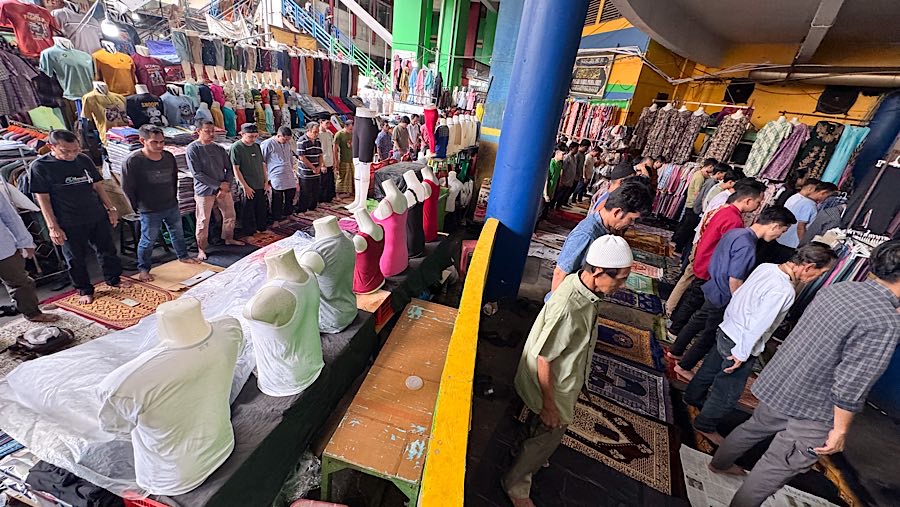 Suasana penuh kekhusyukan tetap tercipta saat suara adzan menggema di tengah hiruk-pikuk pasar. (Bloomberg Technoz/Andrean Kristianto)