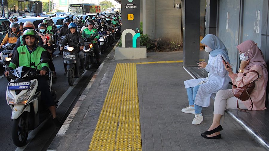 Warga duduk di halte kawasan Gatot Subroto, Jakarta, Rabu (12/3/2025). (Bloomberg Technoz/Andrean Kristianto)