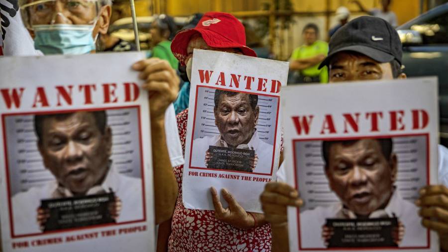 Orang-orang memegang foto mantan Presiden Filipina Rodrigo Duterte di luar Kantor Kejaksaan Kota Quezon. (Bloomberg)