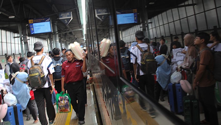 Pramuantar mengankat barang pemudik kereta api jarak jauh di Stasiun Pasar Senen, Jakarta, Rabu (26/3/2025). (Bloomberg Technoz/Andrean Kristianto)