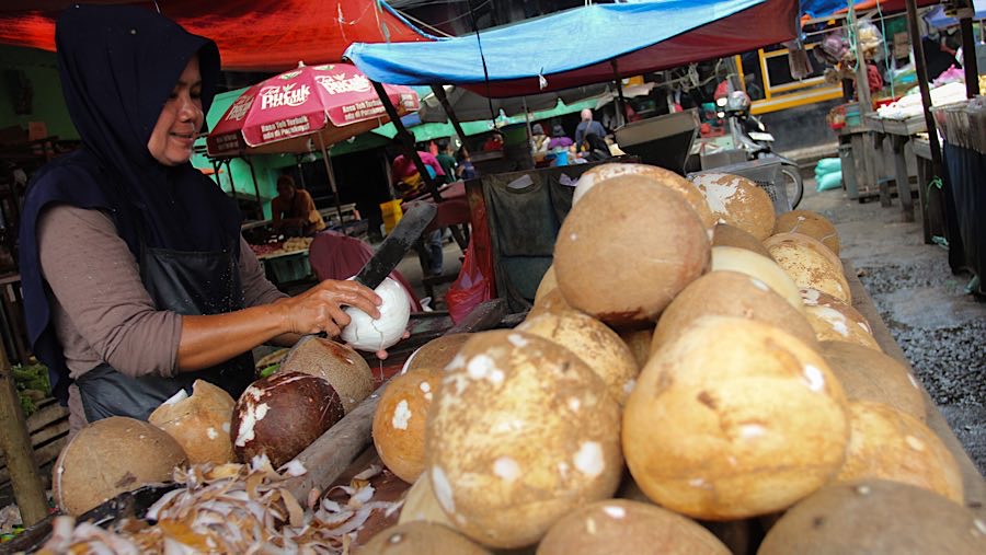Pedagang mengupas kelapa parut di Pasar Minggu, Jakarta, Kamis (17/4/2025). (Bloomberg Technoz/Andrean Kristianto)