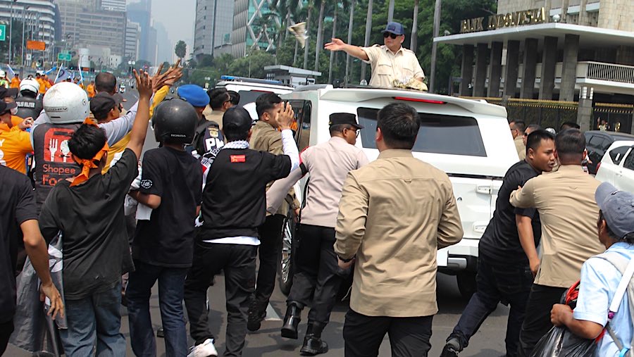 Usai menghadiri perayaan Hari Buruh, Presiden membagikan kaus kepasa masyarakat dari atas mobilnya. Bloomberg Technoz/Andrean Kristianto)