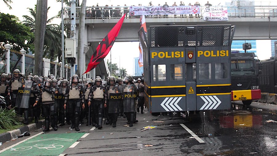 Dari kerumunan terlihat peserta aksi menyalakan kembang api serta melempar botol dan batu. (Bloomberg Technoz/Andrean Kristianto)