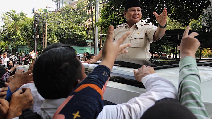 Warga berebut antre untuk bersalaman dengan Presiden Prabowo yang menyapa dari atas mobilnya. (Bloomberg Technoz/Andrean Kristianto)