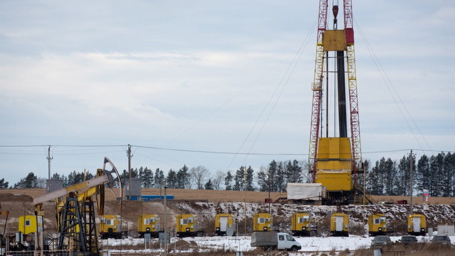 Sebuah dongkrak pompa minyak dan rig pengeboran minyak di kilang minyak Rosneft Oil di Rusia./Bloomberg-Andrey Rudakov