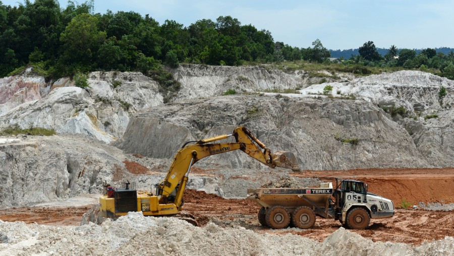 Ekskavator memuat lapisan tanah penutup ke dalam truk pengangkut di lubang tambang di wilayah operasi PT Timah di Sungai Liat, Pulau Bangka./Bloomberg