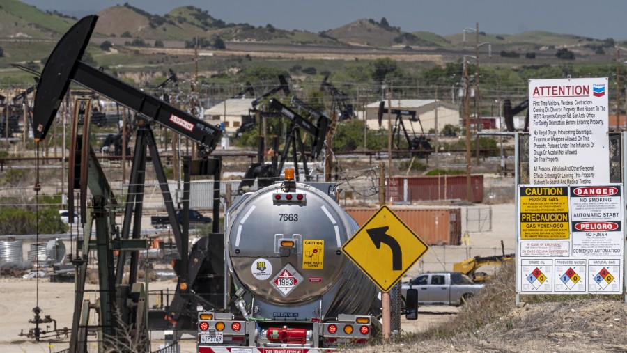 Sebuah truk tangki melaju melewati pompa sumur minyak yang dioperasikan oleh Chevron Corp. di San Ardo, California, AS/Bloomberg-David Paul Morris