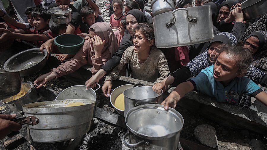 Warga Palestina mengulurkan tangan untuk mendapatkan makanan dari dapur umum di Jabaliya, Gaza utara, Senin (19/5/202). (Ahmad Salem/Bloomberg)