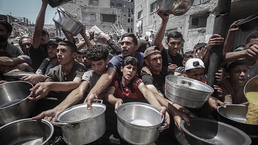 Warga Palestina mengulurkan tangan untuk mendapatkan makanan dari dapur umum di Jabaliya, Gaza utara, Senin (19/5/202). (Ahmad Salem/Bloomberg)
