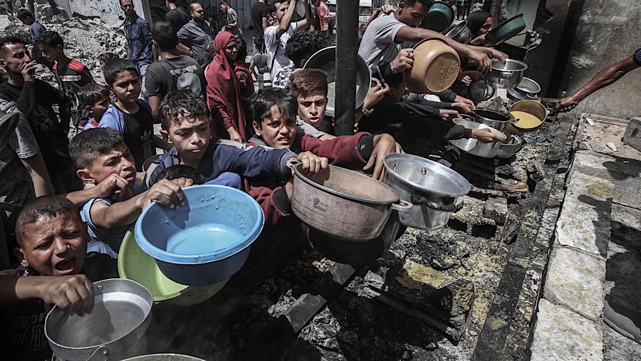 Warga Palestina mengulurkan tangan untuk mendapatkan makanan dari dapur umum di Jabaliya, Gaza utara, Senin (19/5/202). (Ahmad Salem/Bloomberg)