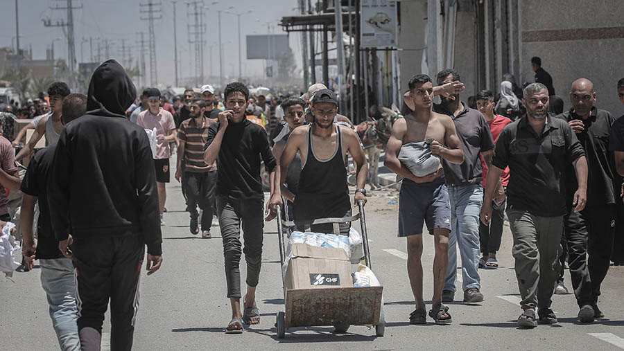 Warga Palestina meembawa kotak bantuan kemanusiaan di Koridor Netzarim, Gaza bagian tengah, Kamis, (29/5/2025). (Ahmad Salem/Bloomberg)