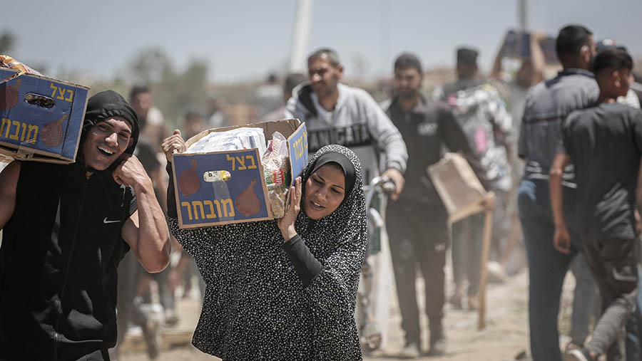 Warga Palestina meembawa kotak bantuan kemanusiaan di Koridor Netzarim, Gaza bagian tengah, Kamis, (29/5/2025). (Ahmad Salem/Bloomberg)