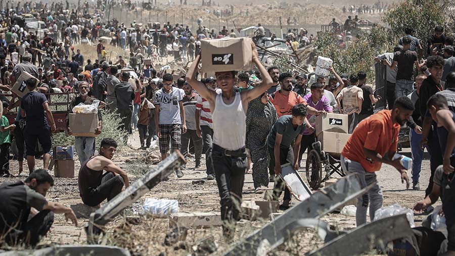 Warga Palestina meembawa kotak bantuan kemanusiaan di Koridor Netzarim, Gaza bagian tengah, Kamis, (29/5/2025). (Ahmad Salem/Bloomberg)