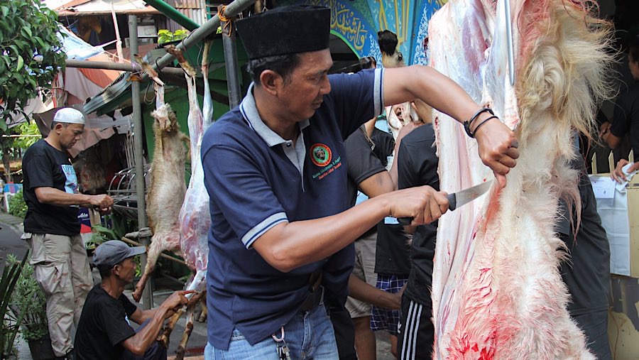 Warga memotongi daging kurban di kawasan Kebon Melati, Jakarta, Jumat (6/6/2025). (Bloomberg Technoz/Andrean Kristianto)