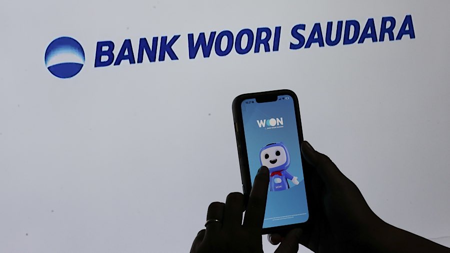 Warga membuka aplikasi Bank Woori Saudara di Jakarta, Selasa (10/4/2025). (Bloomberg Technoz/Andrean Kristianto)