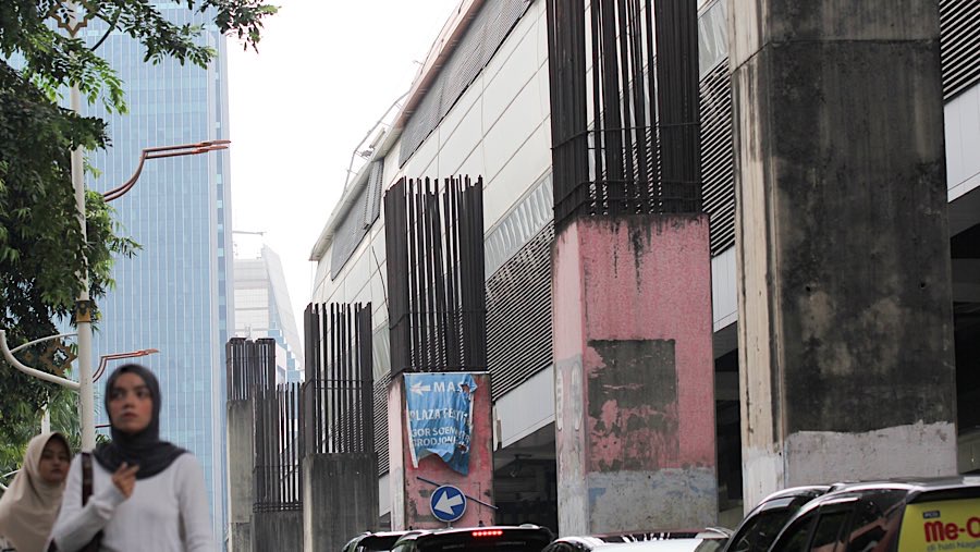 Warga melintas di dekat tiang proyek monorel Jakarta di kawasan Jalan HR Rasuna Said, Rabu (11/6/2025). (Bloomberg Technoz/Andrean Kristianto)