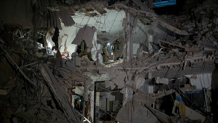 Tim penyelamat Israel berada di bangunan yang rusak akibat serangan rudal balistik Iran di Ramat Gan, Israel, Jumat (13/6/2025). (Kobi Wolf/Bloomberg)