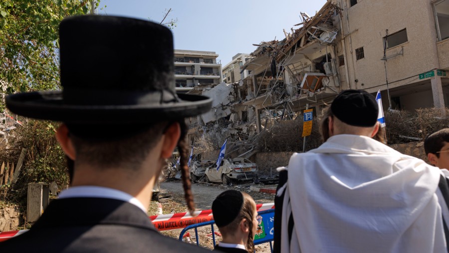 Umat Yahudi Ortodoks melihat kerusakan bangunan yang terkena serangan rudal balistik Iran di Ramat Gan, Israel, Sabtu (14/6/2025)./Bloomberg