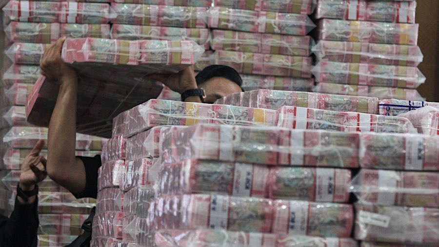 Petugas merapihkan barang bukti uang saat konfrensi pers kasus korupsi ekspor CPO di Kejagung, Selasa (17/6/2025). (Bloomberg Technoz/Andrean K)