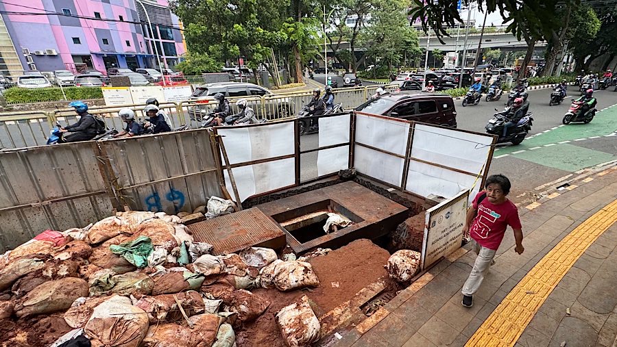 Warga berjalan disamping proyek galian di Jalan Prof. DR. Soepomo, Jakarta, Selasa (24/6/2025). (Bloomberg Technoz/Andrean Kristianto)