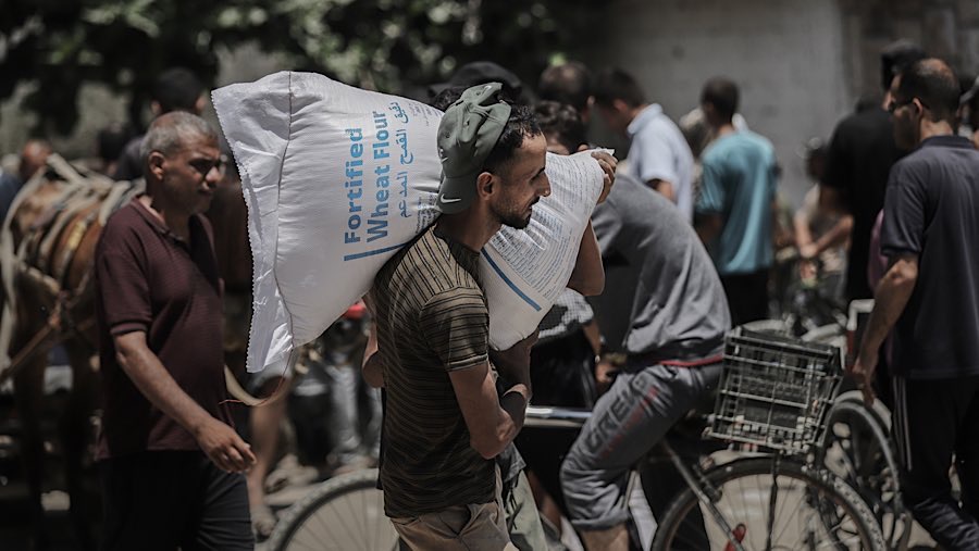 Warga membawa karung tepung yang dikumpulkan dari titik distribusi Program Pangan Dunia (WFP) di Kota Gaza, Kamis (26/6/2025). (Ahmad Salem/Bloomberg)