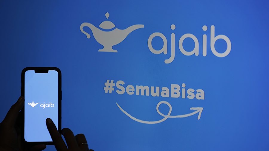 Warga menggunakan gawai dengan latar logo Ajaib Sekuritas di Jakarta, Selasa (1/7/2025). (Bloomberg Technoz/Andrean Kristianto)