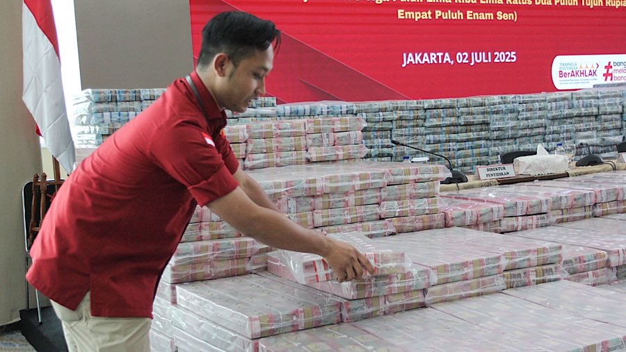 Petugas merapihkan uang sitaan tindak pidana korupsi pemberian fasilitas CPO di Kejagung, Rabu (2/7/2025). (Bloomberg Technoz/Andrean Kristianto)
