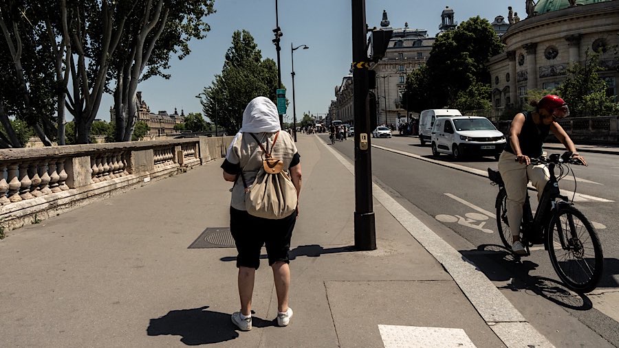 Warga melindungi kepalanya dari terik matahari saat gelombang panas melanda kota Paris, Prancis, Selasa (1/7/2025). (Anita Pouchard Serra/Bloomberg)