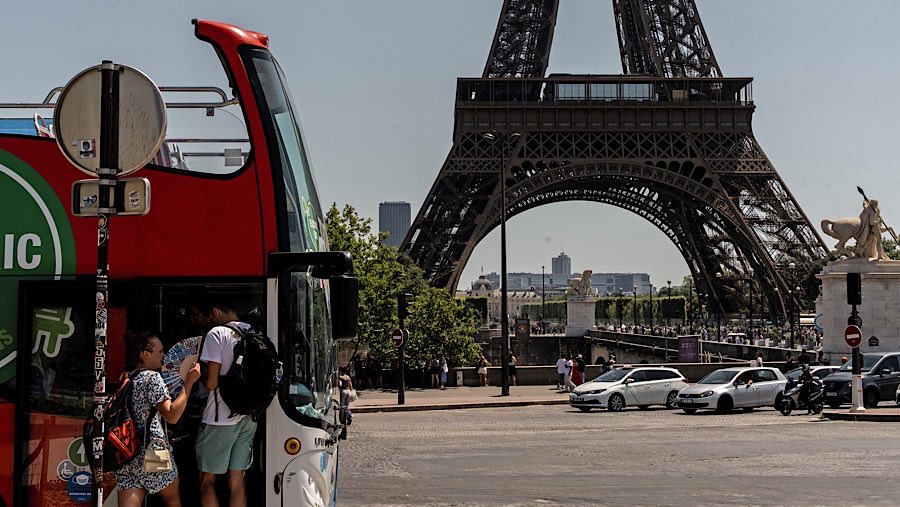 Warga menggunakan kipas menaiki bus di dekat Menara Eiffel saat gelombang panas di Paris, Prancis, Selasa (1/7/2025). (Anita Pouchard Serra/Bloomberg)