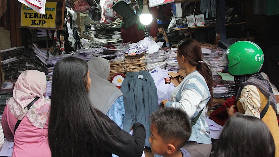 Warga memilih seragam sekolah di Pasar Jatinegara, Jakarta, Senin (7/7/2025). (Bloomberg Technoz/Andrean Kristianto)