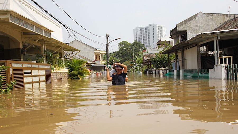 Warga menerobos banjir di Perumahan Ciledug Indah I, Tangerang, Banten, Selasa (8/7/2025). (Bloomberg Technoz/Andrean Kristianto)
