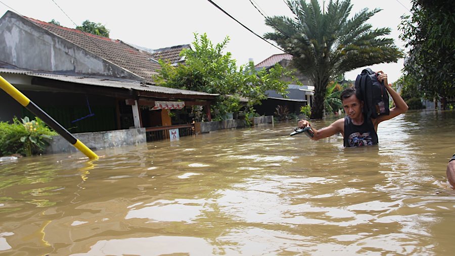 Warga menerobos banjir di Perumahan Ciledug Indah I, Tangerang, Banten, Selasa (8/7/2025). (Bloomberg Technoz/Andrean Kristianto)