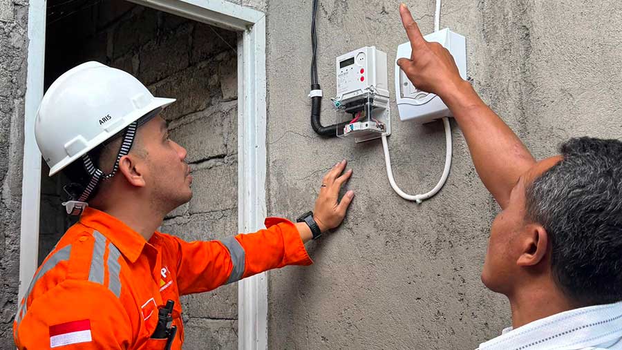 Salah satu penerima manfaat penyambungan listrik gratis program LUTD di Karangasem, Bali, I Wayan Polos (kanan) mendampingi petugas PLN. (PLN)