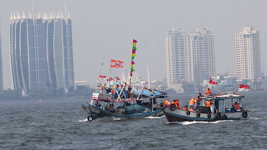 Warga dengan menggunakan kapal berlayar menuju lokasi pelarungan sesajen di Jakarta, Selasa (22/7/2025). (Bloomberg Technoz/Andrean Kristianto) 