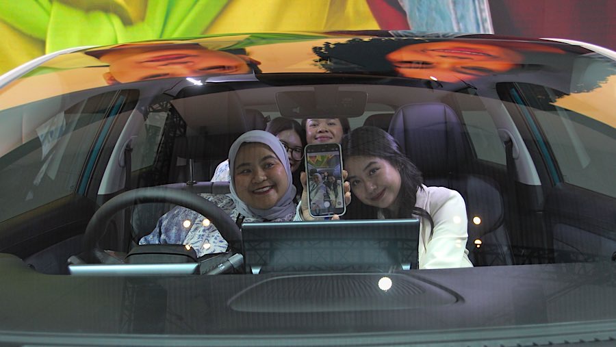 Pengunjung berswafoto di dalam mobil AION UT saat pameran otomotif GIIAS 2025 di ICE BSD, Rabu (23/7/2025). (Bloomberg Technoz/Andrean Kristianto)