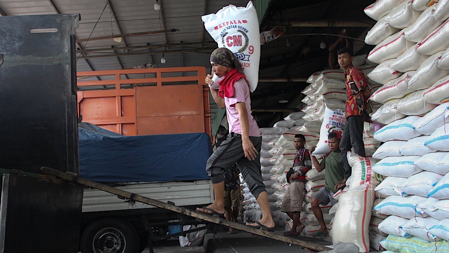 Pekerja mengangkut karung beras di Pasar Induk Beras Cipinang, Jakarta, Jumat (25/7/2025). (Bloomberg Technoz/Andrean Kristianto)