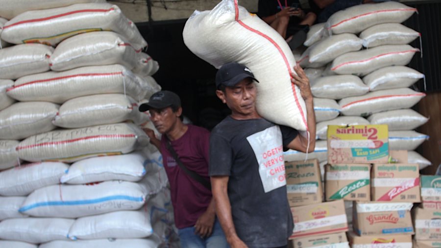 Pekerja mengangkut karung beras di Pasar Induk Beras Cipinang, Jakarta, Jumat (25/7/2025). (Bloomberg Technoz/Andrean Kristianto)