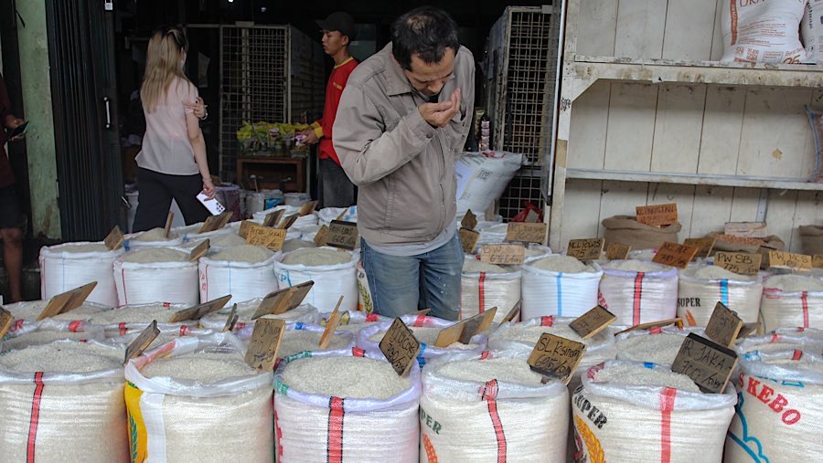 Warga memiih beras yang dijual di Pasar Induk Beras Cipinang, Jakarta, Jumat (25/7/2025). (Bloomberg Technoz/Andrean Kristianto)