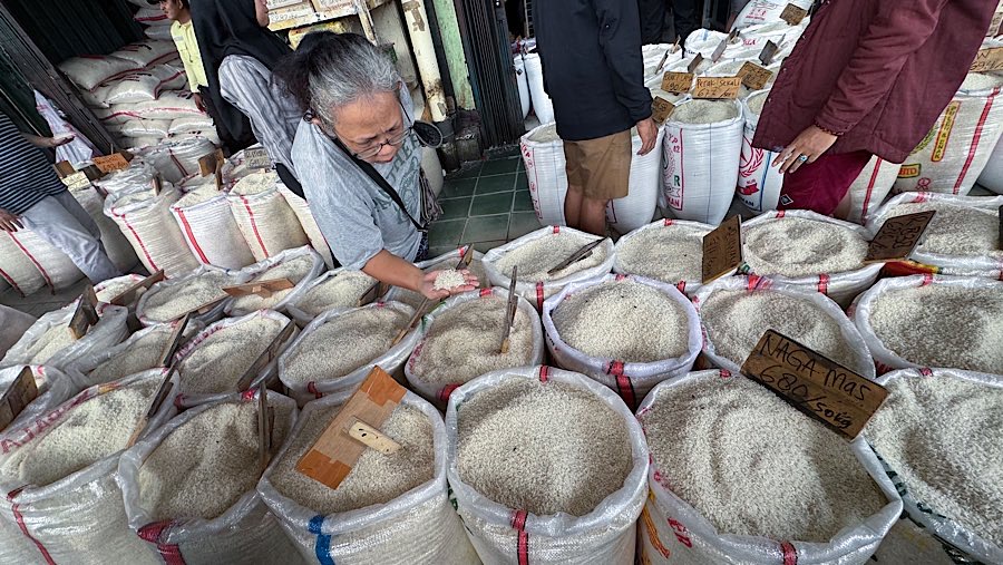 Warga memiih beras yang dijual di Pasar Induk Beras Cipinang, Jakarta, Jumat (25/7/2025). (Bloomberg Technoz/Andrean Kristianto)