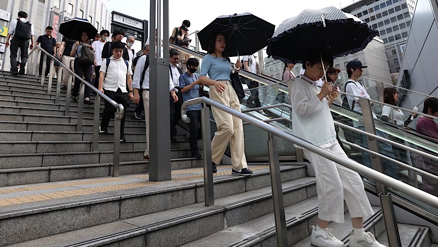 Pejalan kaki berjalan membawa payung saat suhu tinggi di distrik Umeda, Osaka, Jepang, Kamis (31/7/2025). (Buddhika Weerasinghe/Bloomberg)