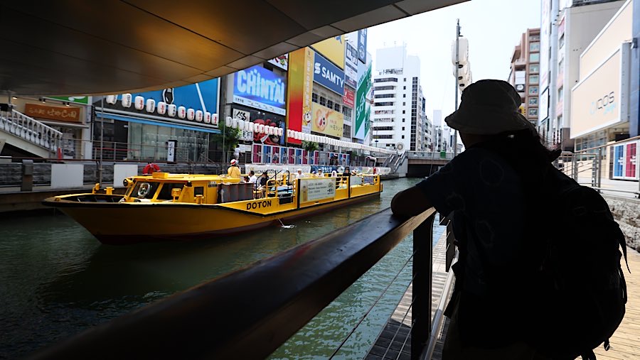 Turis berdiri di bawah pohon saat suhu tinggi di sepanjang Kanal Dotonbori, Osaka, Jepang, Kamis (31/7/2025). (Buddhika Weerasinghe/Bloomberg)
