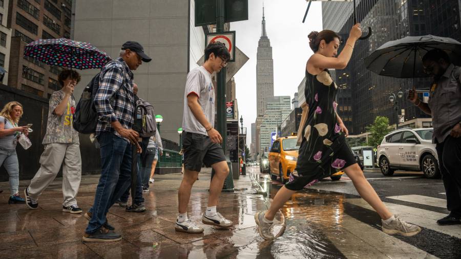 Pejalan kaki saat hujan badai di New York pada hari Kamis (31/7). (Fotografer: Victor J. Blue/Bloomberg)