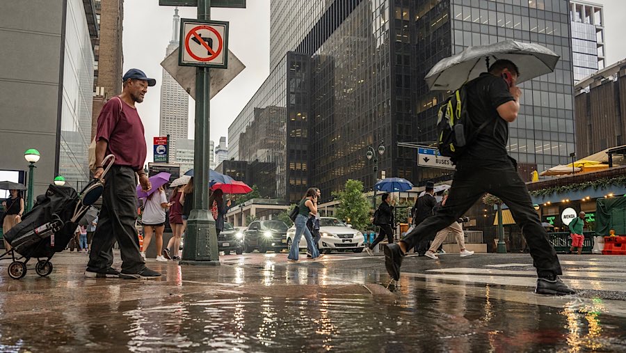 Warga berjalan saat hujan badai di New York, AS, Kamis (31/7/2025). (Victor J. Blue/Bloomberg)
