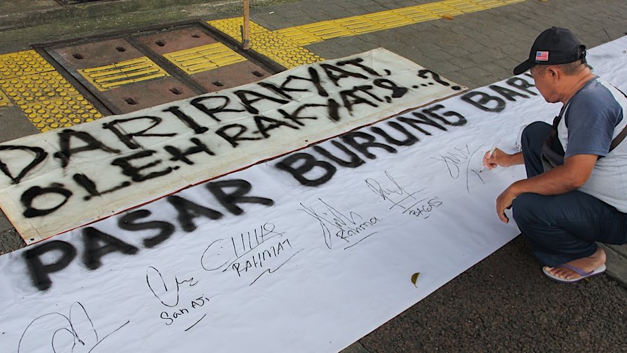 Sebagai aksi penolakan, para pedagang menandatangani petisi diatas kain putih. (Bloomberg Technoz/Andrean Kristianto)