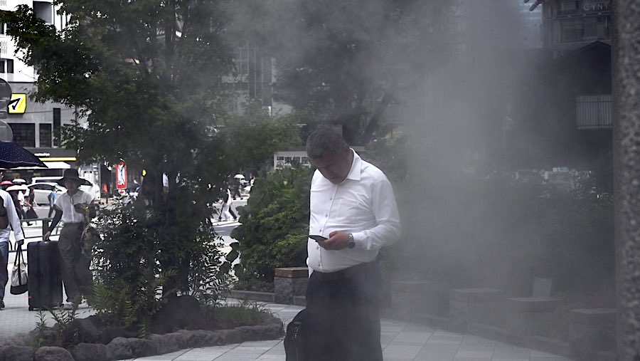 Warga menyejukkan diri di bawah semprotan air saat suhu tinggi melanda Tokyo di distrik Ginza, Jepang, Rabu (6/8/2025). (Soichiro Koriyama/Bloomberg)