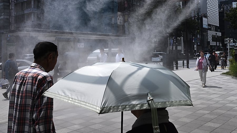 Warga menyejukkan diri di bawah semprotan air saat suhu tinggi melanda Tokyo di distrik Ginza, Jepang, Rabu (6/8/2025). (Soichiro Koriyama/Bloomberg)