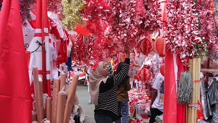 Calon pembeli melihat pernak-pernik kemerdekaan di Pasar Jatinegara, Jakarta, Jumat (8/8/2025). (Bloomberg Technoz/Andrean Kristianto)