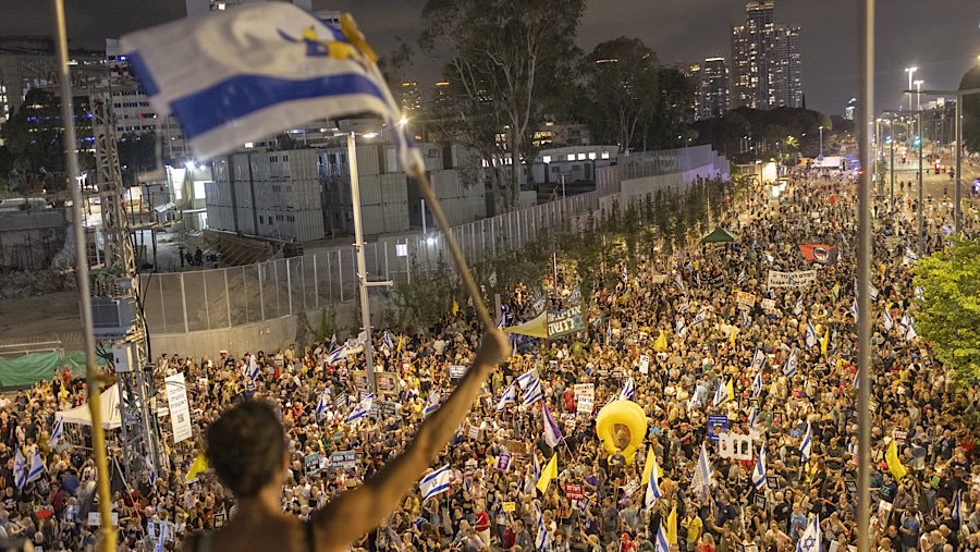 Para demonstran mengibarkan bendera Israel, membawa poster bergambar sandera, dan spanduk yang mengkritik pemerintah. (Kobi Wolf/Bloomberg)