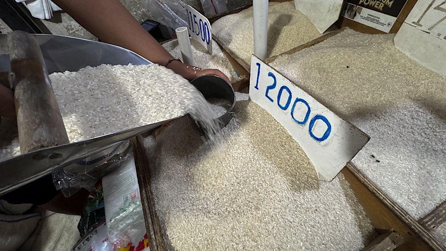 Pedagang menuangkan beras di salah satu warung sembako kawasan Jati Padang, Jakarta, Selasa (12/8/2025) (Bloomberg Technoz/Andrean Kristianto)